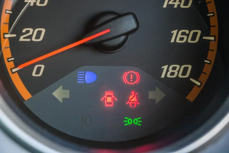Detailed view of a car speedometer with illuminated warning indicators.